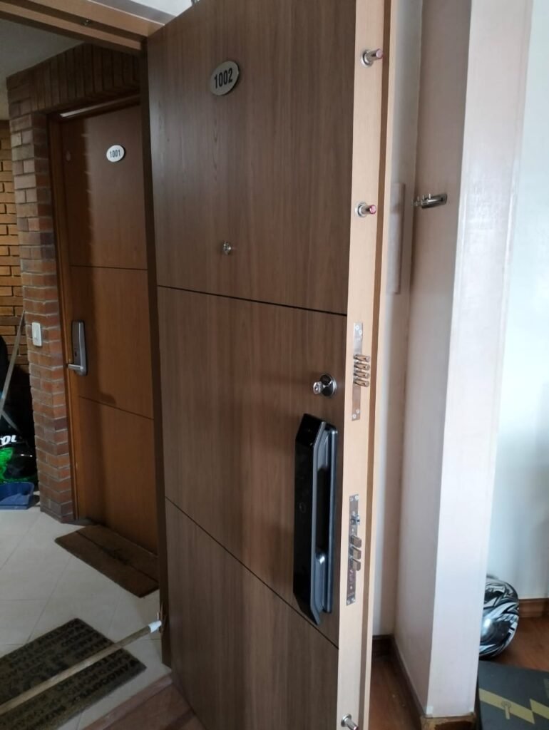 Cerradura inteligente instalada en puerta de seguridad en Bogotá con teclado táctil y lector de huella